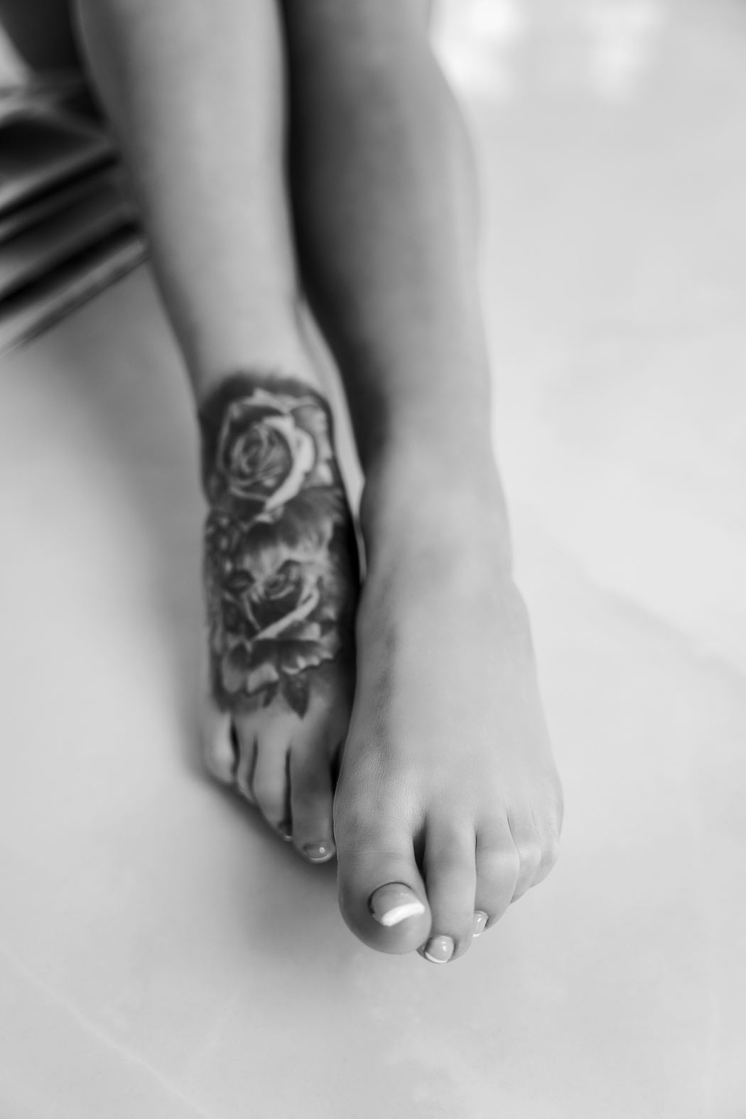 Black and white detail of a tattooed foot on white marble