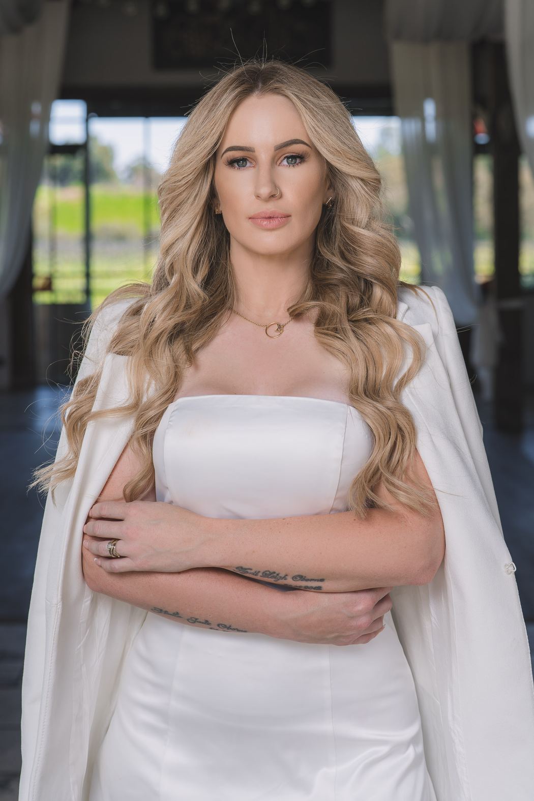 Woman in a white strapless dress and blazer, arms folded