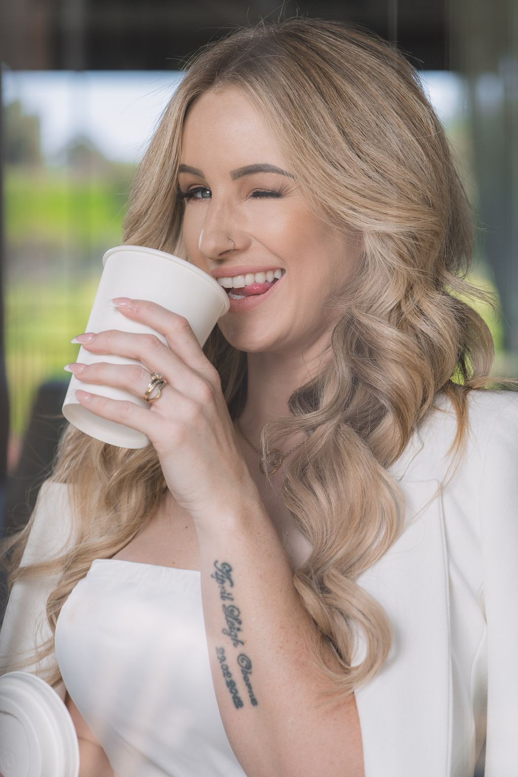 Woman laughing as she drinks from a coffee cup