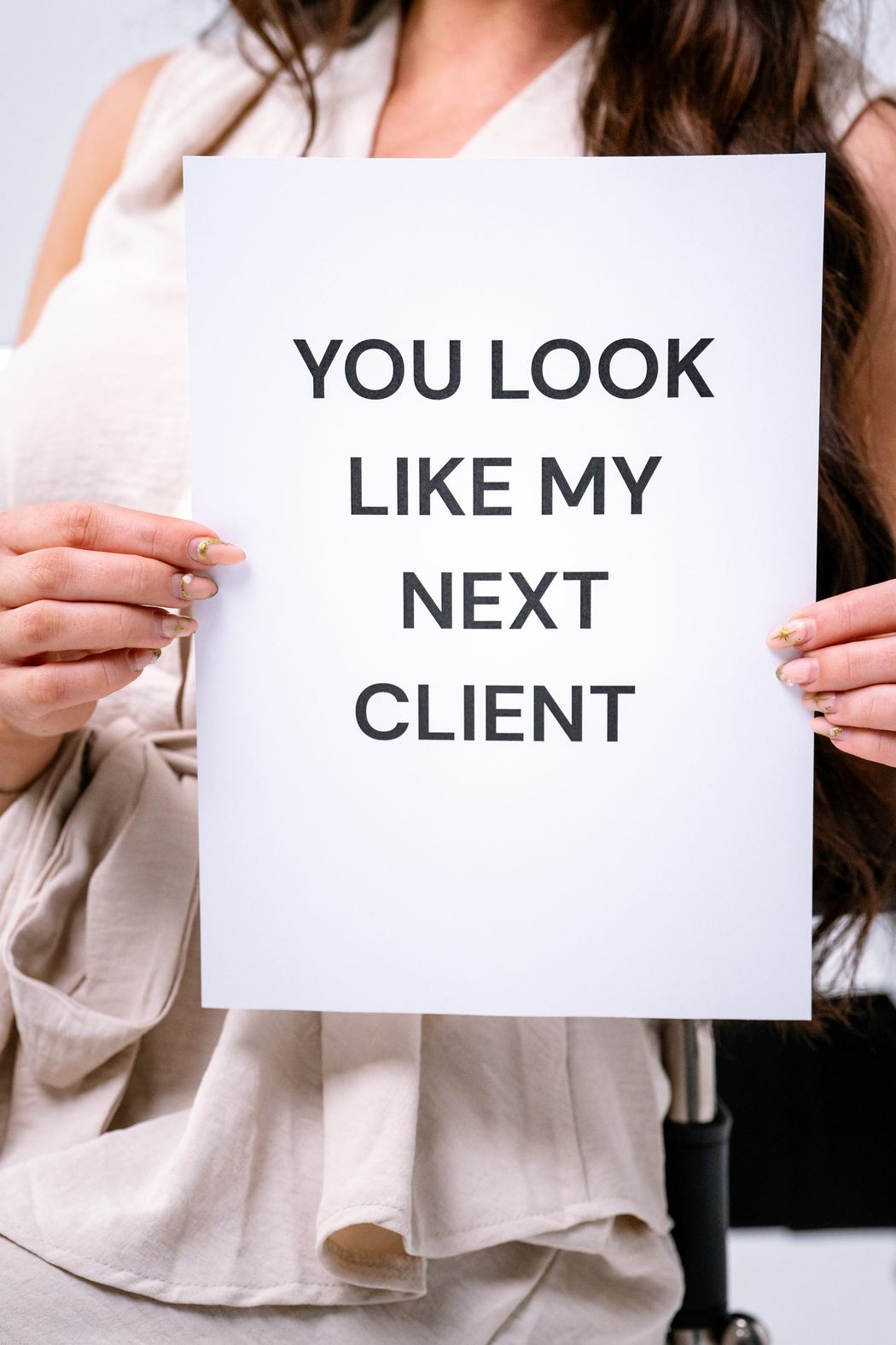Woman holding a sign that reads You look like my next client