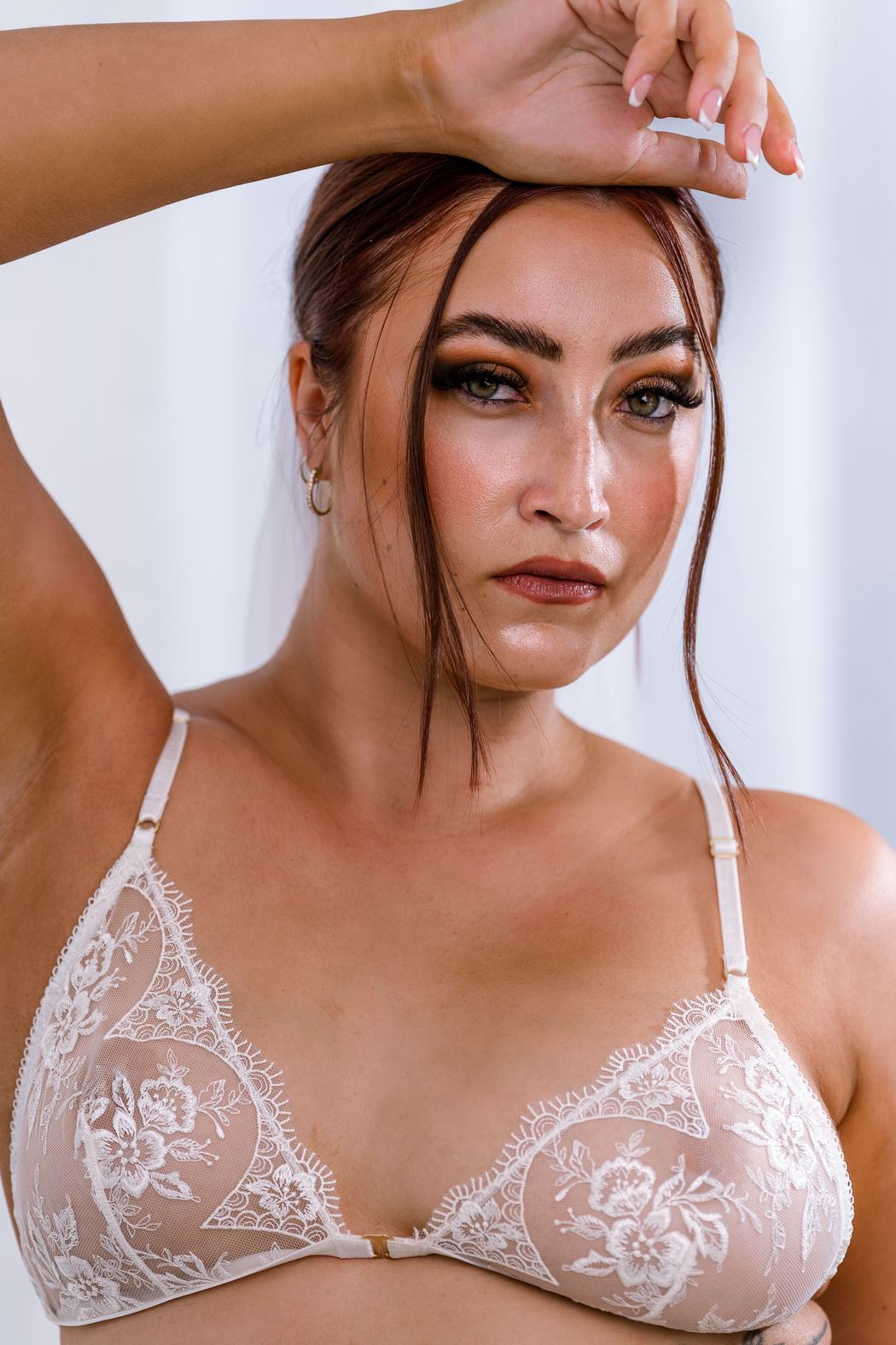 Bride-to-be in an ivory lace bra, hand raised to her hair