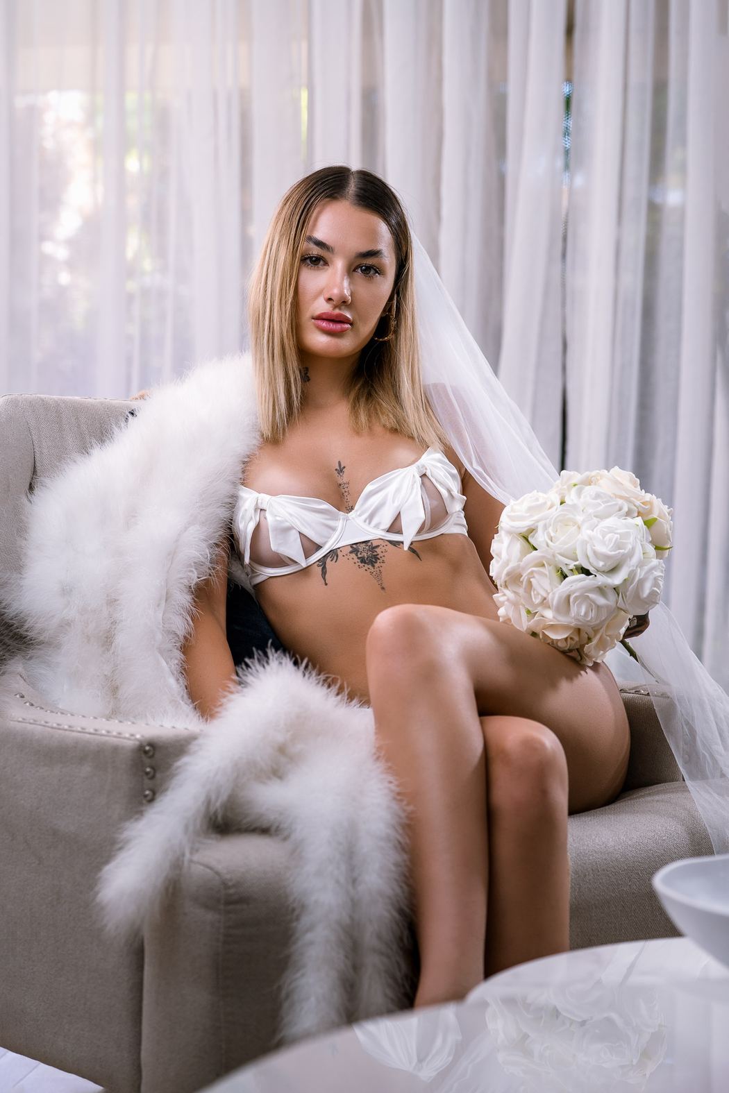 Bride seated with a white feather boa, looking to camera