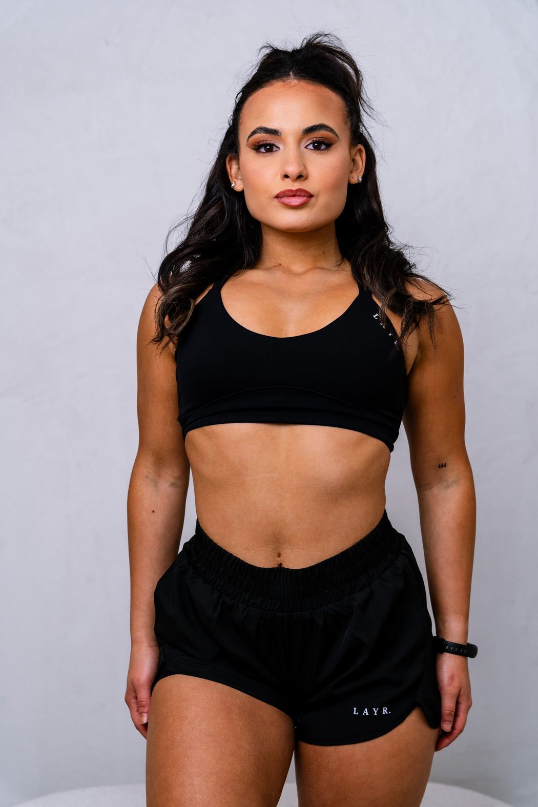Woman in black sports bra and shorts, studio portrait