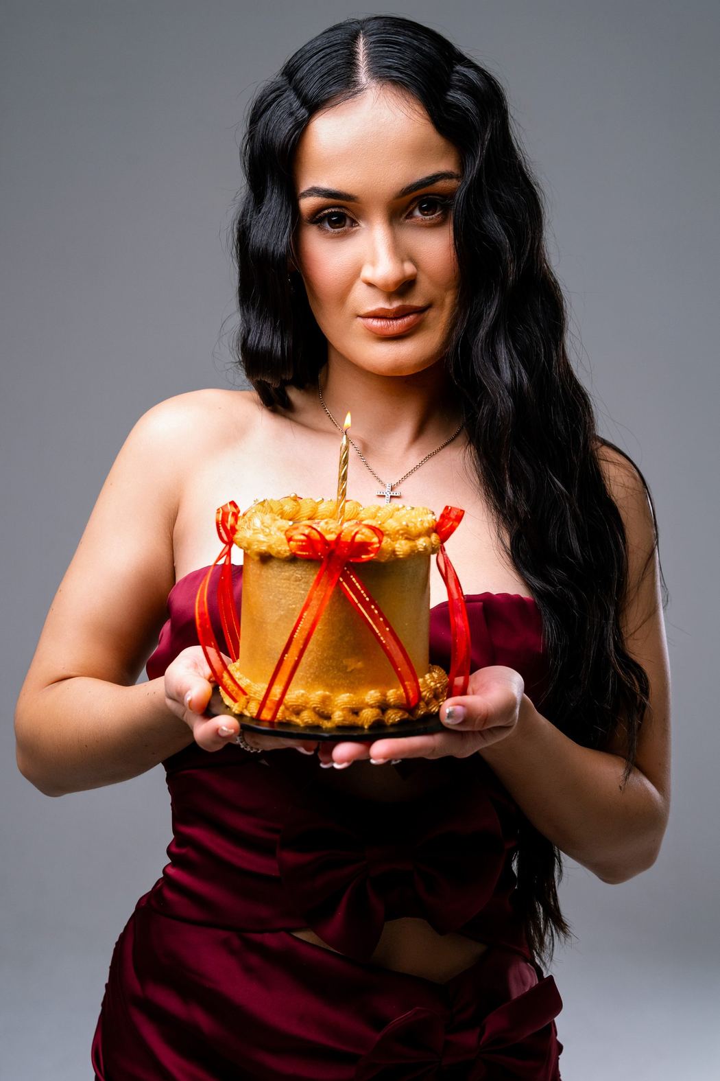 Woman in burgundy holding a small decorated cake