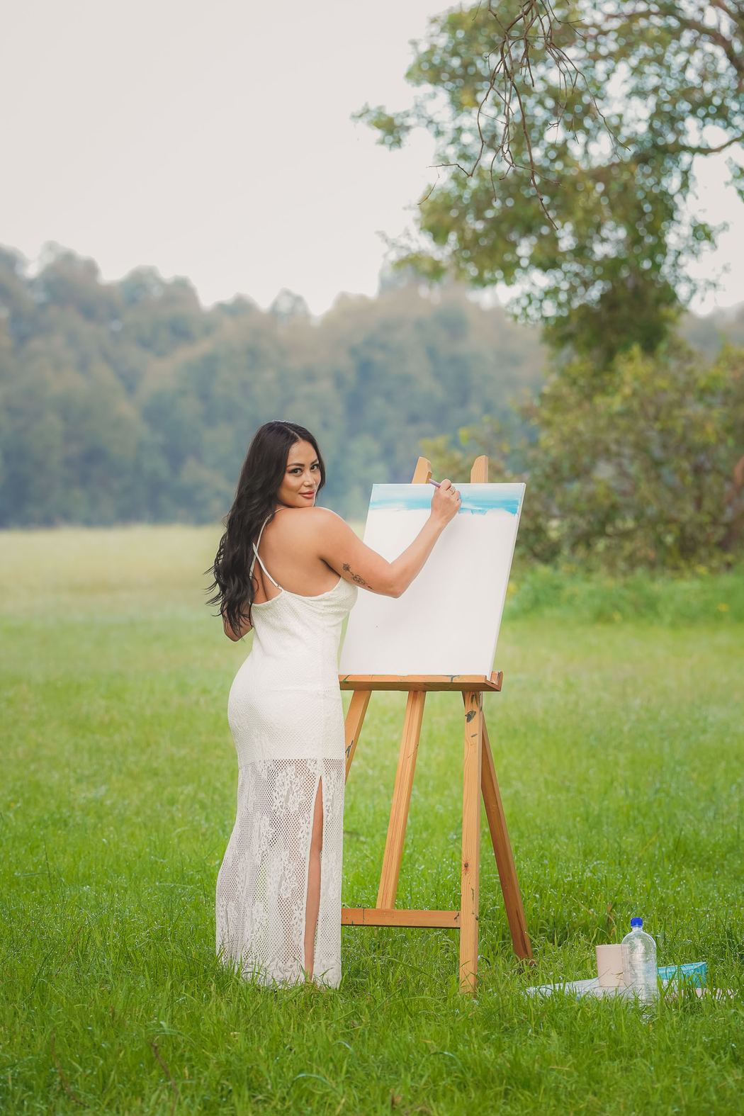 Woman painting at an easel in an open field
