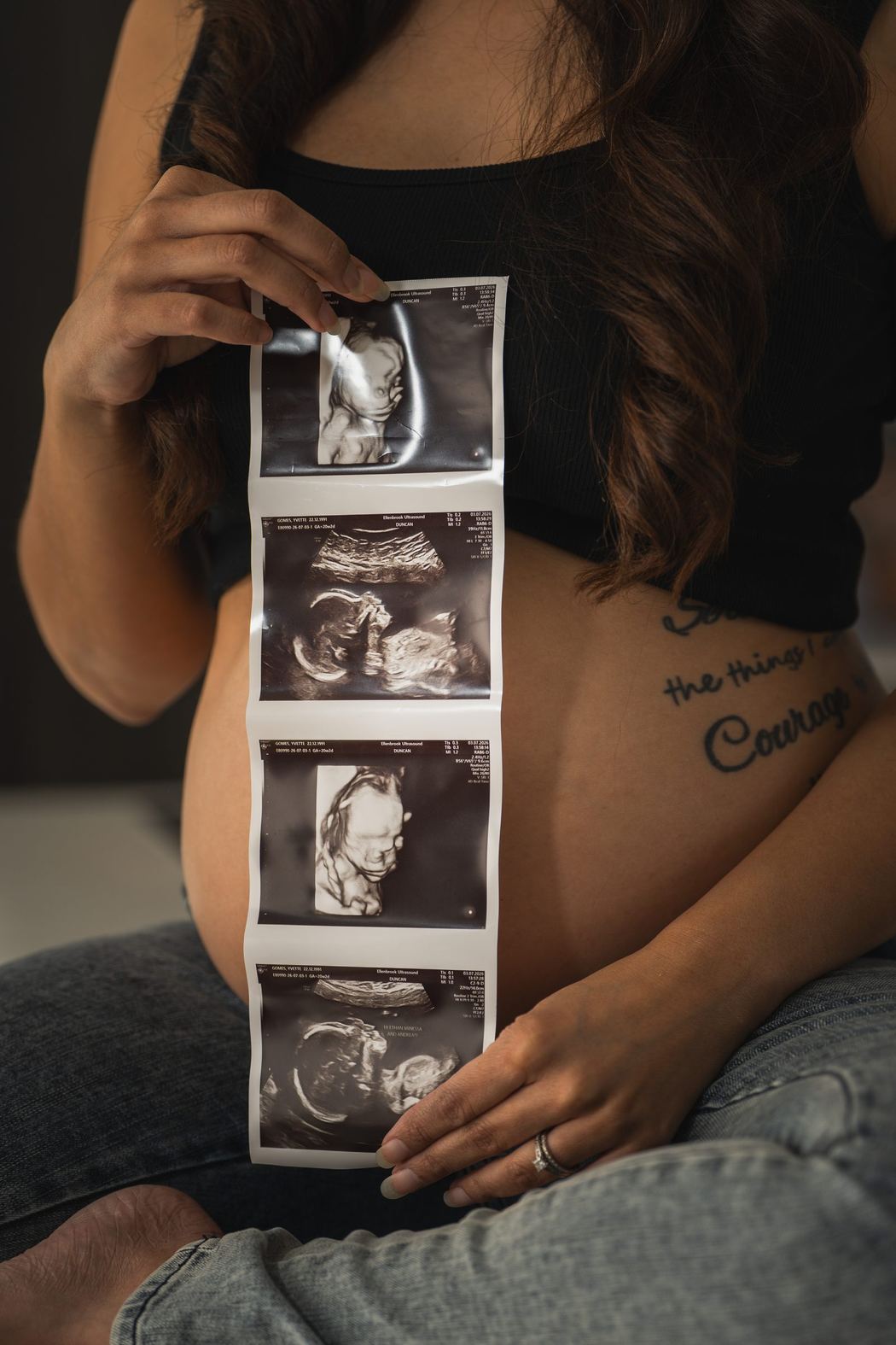Ultrasound photos held against a pregnant belly