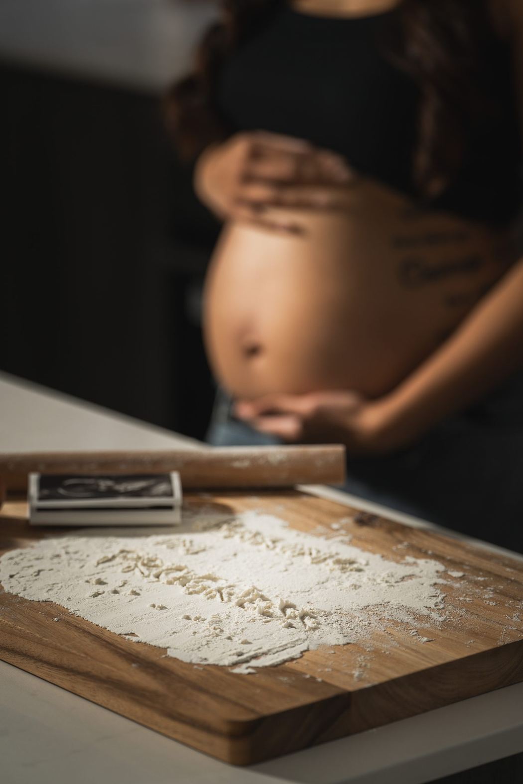 Pregnant belly behind flour written with the word Strength on a board