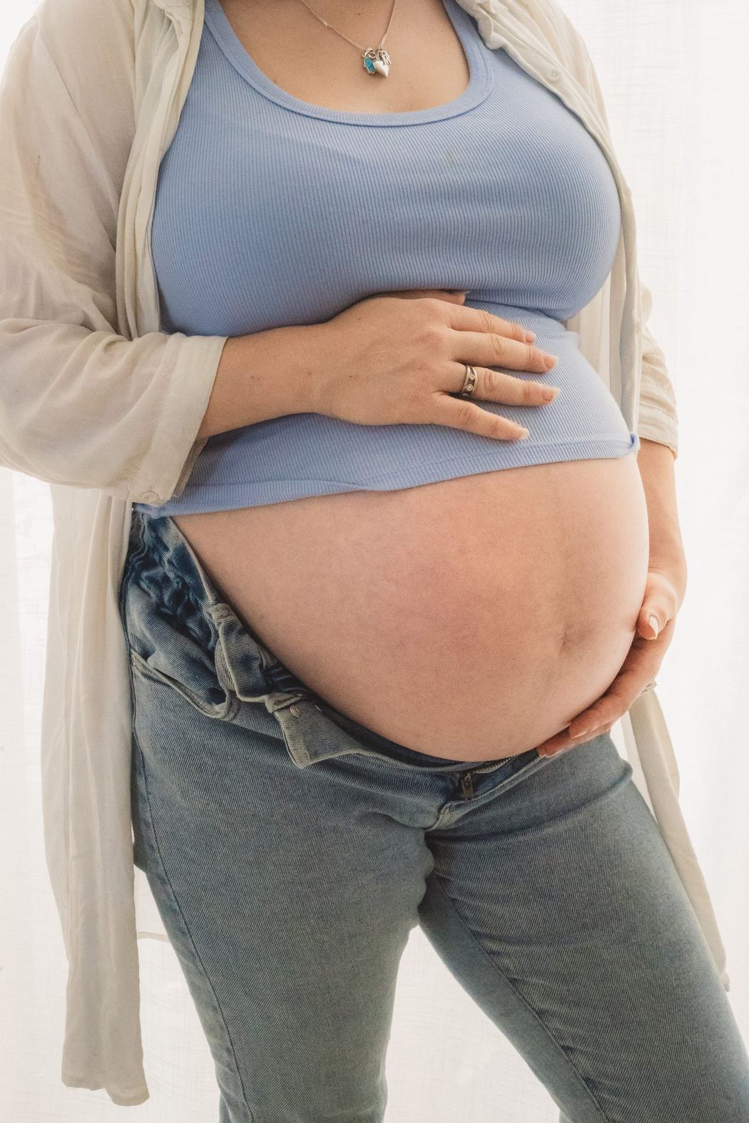 Expecting mother in a blue top and cream cardigan
