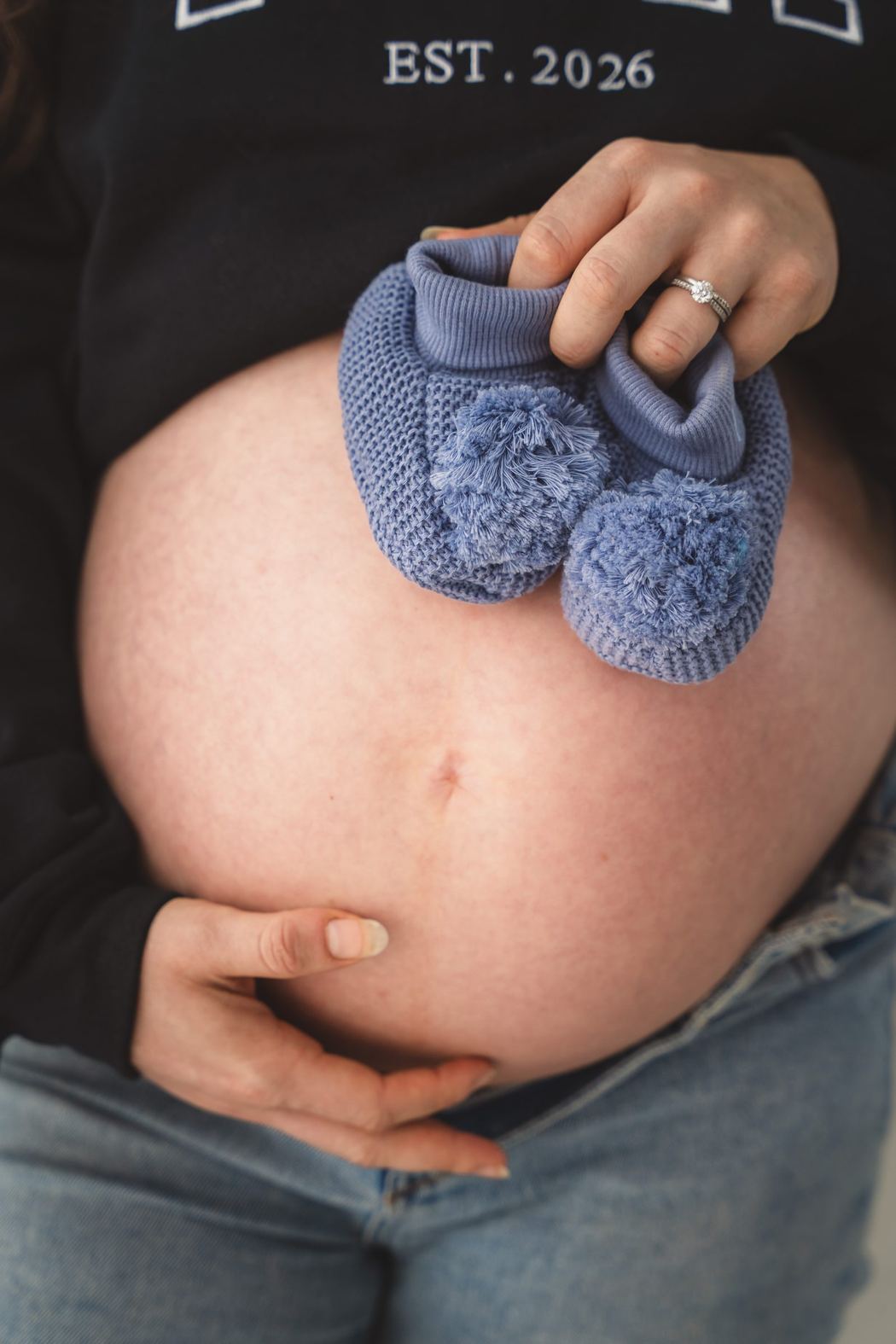 Baby booties held against a pregnant belly